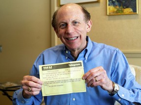 In a Friday, March 1 2019 photo, Robert Fink holds up a telegram from a family friend congratulating him on his 1969 graduation from the University of Michigan at his home in Huntington Woods, Mich. The telegram, delivered to his apartment the day after he moved away from Ann Arbor, was recovered 50 years later by an employee of a downtown Ann Arbor company in a filing cabinet bought from the University of Michigan.