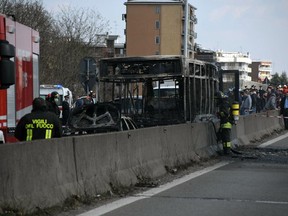 Firefighters stand by the gutted remains of a bus in San Donato Milanese, near Milan, Italy, March 21, 2019. Italian authorities say a bus driver transporting schoolchildren stopped his vehicle on a provincial highway, told the passengers to get off and then doused the interior with gasoline and set it on fire. Italian media reported that the driver, an Italian of Senegalese origin, was immediately apprehended.