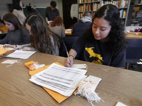 Ximena Mancilla, who came to the U.S. from Mexico in 2011 and a freshman at the University of Michigan, fills out a toe tag in Ann Arbor, Mich., Wednesday, March 27, 2019. A giant map of Arizona in the hallway of a University of Michigan building steadily fills with orange and tan cards. On closer inspection, they are toe tags, traditionally attached to bodies in morgues, representing the roughly 3,000 people who have died in the past two decades illegally crossing from Mexico into the U.S. in the Sonoran Desert. The tan tags are for remains that have been identified; the orange are unidentified.