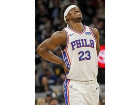 Philadelphia 76ers forward Jimmy Butler grabs his back and grimaces in the first quarter of an NBA basketball game against the Minnesota Timberwolves Saturday, March 30, 2019, in Minneapolis.