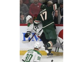 Dallas Stars' Ben Lovejoy, left, is checked into the boards by Minnesota Wild's Marcus Foligno in the first period of an NHL hockey game Thursday, March 14, 2019, in St. Paul, Minn.