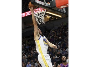 Golden State Warriors' Klay Thompson, left, lays up as Minnesota Timberwolves' Josh Okogie, lower right, watches in the second half of an NBA basketball game Tuesday, March 19, 2019, in Minneapolis. The Warriors won 117-107. Thompson scored 28 points.