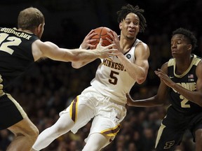 Minnesota's guard Amir Coffey controls the ball through the defense of Purdue's Evan Boudreaux and Eric Hunter Jr. during the first half of an NCAA basketball game Tuesday, March 5, 2019, in Minneapolis.