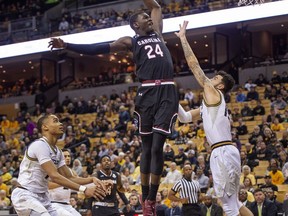 South Carolina's Keyshawn Bryant, center, dunks over Missouri's Jordan Geist, right, after he dribbles past Xavier Pinson, left, during the first half of an NCAA college basketball game Saturday, March 2, 2019, in Columbia, Mo.