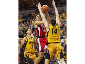 Mississippi's KJ Buffen, center, shoots between Missouri's Reed Nikko, right, and Ronnie Suggs, left, during the first half of an NCAA college basketball game Saturday, March 9, 2019, in Columbia, Mo.