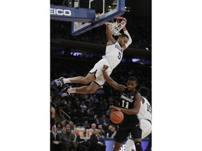 Villanova's Phil Booth (5) hangs from the rim over Providence's Alpha Diallo (11) after after dunking the ball during the first half of an NCAA college basketball game in the Big East conference tournament, Thursday, March 14, 2019, in New York.