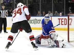 New York Rangers goaltender Henrik Lundqvist (30) deflects the puck as New Jersey Devils' Eric Tangradi looks for a rebound during the first period of an NHL hockey game Saturday, March 9, 2019, at Madison Square Garden in New York.