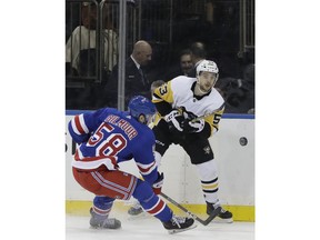 Pittsburgh Penguins center Teddy Blueger (53), of Latvia, passes the puck as New York Rangers defenseman John Gilmour (58) moves in during the first period of an NHL hockey game in New York, Monday, March 25, 2019.