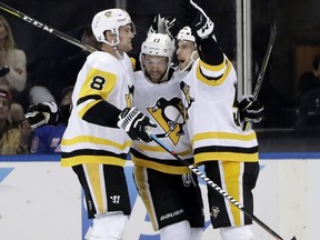 Pittsburgh Penguins center Teddy Blueger, right, of Latvia, celebrates with defenseman Brian Dumoulin (8) and right wing Bryan Rust (17) after scoring a goal against the New York Rangers during the second period of an NHL hockey game in New York, Monday, March 25, 2019.