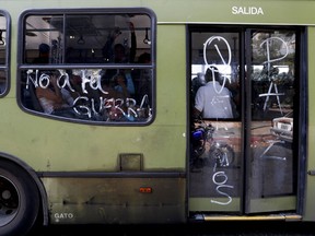 Passengers ride on a bus with messages scrawled on it that read in Spanish "No to war," and "We want peace," in Caracas, Venezuela, Thursday, March 14, 2019. With long lines at the stops of public transport and crowds of people at the entrance of some banking agencies, Venezuelans returned to activity on Thursday after four days of paralysis as a result of the biggest blackout in the country's history.