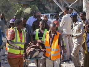 Somalis carry away the body of a civilian victim who was shot dead by gunmen during a suicide car bomb attack on a government building in the capital Mogadishu, Somalia, Saturday, March 23, 2019. Al-Shabab gunmen stormed the government building after a suicide car bombing, killing at least five people including the country's deputy labor minister, police said, in the latest attack by Islamic extremist fighters in the Horn of Africa nation.
