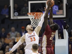 Florida State's Christ Koumadje (21) tries to dunk against Virginia's Jack Salt (33) during the first half of an NCAA college basketball game in the Atlantic Coast Conference tournament in Charlotte, N.C., Friday, March 15, 2019.