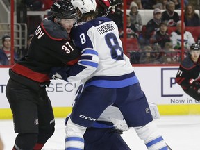 Carolina Hurricanes' Andrei Svechnikov (37), of Russia, struggles with Winnipeg Jets' Jacob Trouba (8) over Jets goalie Laurent Brossoit during the first period of an NHL hockey game in Raleigh, N.C., Friday, March 8, 2019.