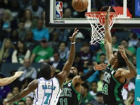 Charlotte Hornets guard Dwayne Bacon (7) reaches for a basket while being covered by Boston Celtics defenders Kyrie Irving (11) and Robert Williams (44) in the first half of an NBA basketball game Saturday, March 23, 2019, in Charlotte, N.C.