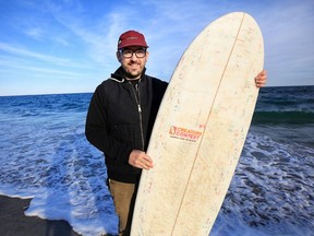 In this undated photo, Korey Nolan of Hampton Falls, N.H., stands with the surfboard he made using hundreds of Dunkin' Donuts coffee cups and other single-use materials. He compressed the raw materials together and finished the board using bamboo, epoxy and more.