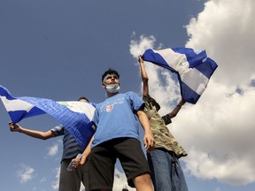 Young men wave national flags during a protest demanding the government release hundreds of protesters held in custody since 2018, in Managua, Nicaragua, Saturday, March 16, 2019. Nicaragua's government banned opposition protests in September and police broke up Saturday's attempt at a demonstration.
