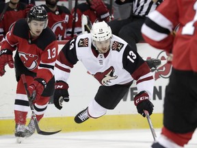 Arizona Coyotes center Vinnie Hinostroza, right, goes airborne while competing for the puck with New Jersey Devils center Nico Hischier, of Switzerland, during the first period of an NHL hockey game, Saturday, March 23, 2019, in Newark, N.J.
