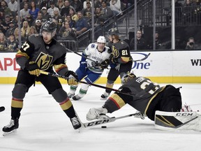 Vegas Golden Knights goaltender Marc-Andre Fleury (29) dives to block the puck with defenseman Shea Theodore (27) covering during the first period of an NHL hockey game against the Vancouver Canucks Sunday, March 3, 2019, in Las Vegas.