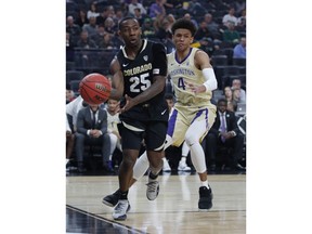 Colorado's McKinley Wright IV passes around Washington's Matisse Thybulle during the first half of an NCAA college basketball game in the semifinals of the Pac-12 men's tournament Friday, March 15, 2019, in Las Vegas.