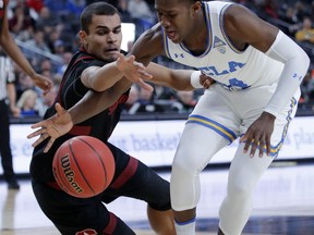 Stanford's Oscar Da Silva, left, and UCLA's David Singleton scramble for the ball during the first half of an NCAA college basketball game in the first round of the Pac-12 men's tournament, Wednesday, March 13, 2019, in Las Vegas.