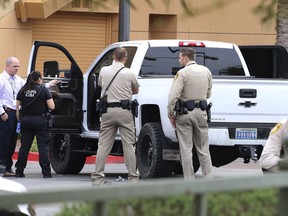 Las Vegas police surround a white pickup truck as they investigate after a pursuit related to the officer-involved shooting that ended at the Golden Nugget hotel-casino on Wednesday, March. 27, 2019, in Las Vegas. Authorities say a Las Vegas police officer shot a jail prisoner who escaped in shackles in a stolen pickup truck after a medical clinic visit and led officers on a wreck-filled chase before running out of gas near downtown casinos.