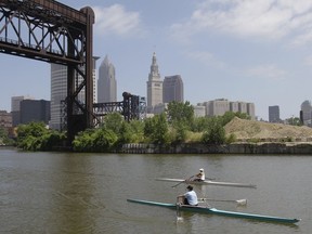 FILE – In this July 12, 2011, file photo, two rowers paddle along the Cuyahoga River in Cleveland.  Federal environmental regulators say fish living in the northeastern Ohio river that became synonymous with pollution when it caught fire in 1969 are now safe to eat. The easing of fish consumption restrictions on the Cuyahoga River was lauded by Republican Gov. Mike DeWine as progress achieved by investing in water quality.