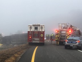 This photo provided by Virginia State Police emergency responders at the scene after a charter bus overturned on an Interstate 95 exit near Kingwood, Va., Tuesday, March 19, 2019.  Virginia State Police said in a statement that the Tao's Travel Inc. bus with 57 people aboard overturned Tuesday morning in Prince George County near Kingwood while traveling from Florida to New York. (Virginia State Police via AP)
