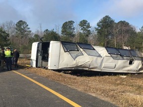 This photo provided by Virginia State Police emergency responders at the scene after a charter bus overturned on an Interstate 95 exit near Kingwood, Va., Tuesday, March 19, 2019. Virginia State Police say in a statement that the Tao's Travel Inc. bus with 57 people aboard overturned on an Interstate 95 exit Tuesday in Prince George County. Police say that as the bus turned onto the exit, it ran off the left side and overturned.    (Virginia State Police via AP)