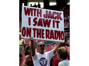 FILE - In this June 18, 2002, file photo, Marty Prather, of Springfield, Mo., holds a sign in rememberance of Jack Buck, the legendary St. Louis Cardinals broadcaster, at Bush Stadium in St. Louis. Unlike basketball or football or other major sports where the action is nonstop, baseball provides many opportunities for broadcasters to fill with stories and personal anecdotes. They weave in updates about their gardens and their travel experiences and their everyday adventures.