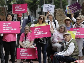 FILE - In this July 10, 2018 file photo, protesters hold signs supporting Planned Parenthood in Seattle, as they demonstrate against President Donald Trump and his choice of federal appeals Judge Brett Kavanaugh as his second nominee to the Supreme Court. On Tuesday, March 5, 2019, the American Medical Association and Planned Parenthood jointly filed a federal court lawsuit challenging a new Trump administration rule for family-planning grants which had been sought by anti-abortion activists.
