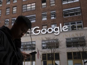 FILE - In this Dec. 17, 2018, file photo a man using a mobile phone walks past Google offices in New York. Google says it plans to launch a video-game streaming platform called Stadia, positioning itself to take on the traditional video-game business.