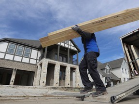 FILE- In this Feb. 20, 2019, file photo a worker carries interior doors to install in a just completed new home in north Dallas. On Tuesday, March 26, the Commerce Department reports on U.S. home construction in February.