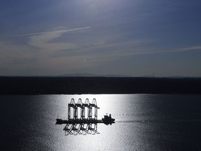 FILE- In this March 5, 2019, file photo the Zhen Hua 31 heavy-lift ship carrying four super-post-Panamax container cranes is silhouetted by the sun as it sails into Commencement Bay in Tacoma, Wash. On Wednesday, March 27, the Commerce Department reports on the U.S. trade gap for January.