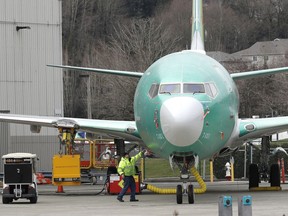FILE- In this March 11, 2019, file photo a worker stands near a Boeing 737 MAX 8 airplane parked at Boeing Co.'s Renton Assembly Plant in Renton, Wash. Boeing soared early in 2019 and lifted the Dow Jones Industrial Average with it. Now concerns about the safety of the newest version of its flagship airplane have halted the momentum.