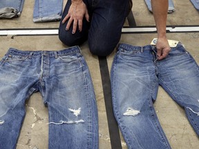 FILE- In this Feb. 9, 2018 photo Bart Sights, head of the Eureka Lab, compares the markings and damage on jeans that he guesses are close to 30 years old, left, to jeans made within a few hours of this photograph at Levi's innovation lab in San Francisco. On Thursday, March 21, 2019, Levi Strauss & Co. is going back to the public markets after 34 years.
