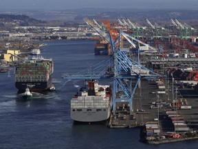 FILE- In this Tuesday, March 5, 2019, file photo the Cape Kortia container ship, left, heads into the Port of Tacoma in Commencement Bay in Tacoma, Wash. On Thursday, March 28, the Commerce Department issues the final estimate of how the U.S. economy performed in the October-December quarter.