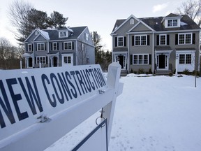 FILE- In this Feb. 21, 2019, file photo a newly constructed homes sit near a sign in Natick, Mass. On Friday, March 29, the Commerce Department reports on sales of new homes in February.