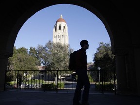 FILE - In this Feb. 15, 2012 file photo, a Stanford University student walks in front of Hoover Tower on the Stanford University campus in Palo Alto, Calif.  Federal authorities have charged college coaches and others in a sweeping admissions bribery case in federal court. The racketeering conspiracy charges were unsealed Tuesday, March 12, 2019, against coaches at schools including Stanford, Wake Forest, Georgetown, the University of Southern California and the University of Southern California and University of California, Los Angeles.