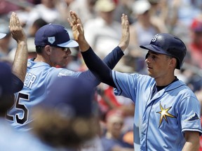FILE - In this Monday, March 11, 2019, file photo, Tampa Bay Rays' Brandon Lowe, right, high-fives teammates after scoring on a two-run single by Willy Adames during the second inning of a spring training baseball game against the Philadelphia Phillies in Clearwater, Fla. Lowe, who made his big league debut last August, has agreed to a $24 million, six-year contract with the Rays.