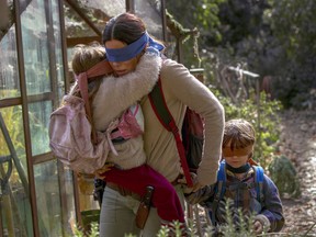 This image released by Netflix shows Sandra Bullock in a scene from the film, "Bird Box." Netflix will remove footage of a real fiery train disaster from its hit post-apocalyptic survival film "Bird Box" months after the streaming giant was criticized for exploiting a tragedy. The stock footage was taken from a 2013 crash in the Quebec town of Lac-Megantic when a train carrying crude oil came off the tracks and exploded into a massive ball of fire, killing 47 people.