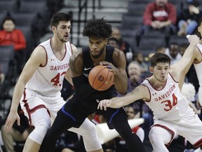 Saint Louis's Hasahn French, center, protects the ball from Davidson's Luke Frampton (34) and Dusan Kovacevic (43) during the first half of an NCAA college basketball game in the semifinal round of the Atlantic 10 men's tournament Saturday, March 16, 2019, in New York.