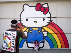 FILE - In this Oct. 30, 2014, file photo, Keith Nunez, left, takes pictures of his wife, Carolina, at the first-ever Hello Kitty fan convention, Hello Kitty Con, at the Geffen Contemporary at MOCA in Los Angeles. Hello Kitty might not have a mouth but she's got a movie deal. Warner Bros.'s New Line Cinema announced Tuesday, March 5, 2019, that it has acquired film rights to Hello Kitty from the Japanese corporation Sanrio.
