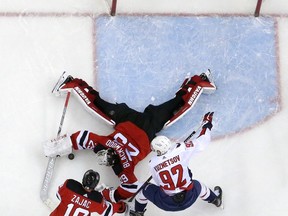 New Jersey Devils goaltender MacKenzie Blackwood (29) dives to make a save against Washington Capitals center Evgeny Kuznetsov (92), of Russia, during the third period of an NHL hockey game, Tuesday, March 19, 2019, in Newark, N.J. Devils' Travis Zajac (19) helps defend on the play. The Capitals won 4-1.