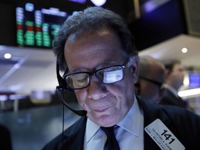 FILE- In this March 12, 2019, file photo a handheld device of trader Sal Suarino is reflected in his glasses as he works on the floor of the New York Stock Exchange. The U.S. stock market opens at 9:30 a.m. EDT on Thursday, March 21.