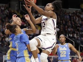 Connecticut guard Christyn Williams (13) goes up for a layup with UCLA guard Ahlana Smith (2) and forward Lajahna Drummer, second left, defending against her during the first half of a regional semifinal game in the NCAA women's college basketball tournament, Friday, March 29, 2019, in Albany, N.Y.