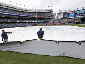 Members of the grounds crew pull the tarp off the field during a rain delay before a baseball game between the New York Yankees and the Baltimore Orioles at Yankee Stadium, Sunday, March 31, 2019, in New York.