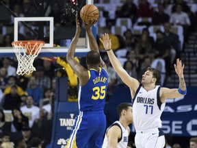 Golden State Warriors forward Kevin Durant (35) shoots as Dallas Mavericks forward Luka Doncic (77) defends in the first half of an NBA basketball game Saturday, March 23, 2019, in Oakland, Calif.
