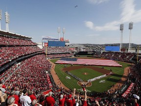 Spectators stand as fighter jets pass over Great American Ball Park during the national anthem before an opening day game between the Cincinnati Reds and the Pittsburgh Pirates, Thursday, March 28, 2019, in Cincinnati.