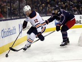 Edmonton Oilers forward Colby Cave, left, controls the puck against Columbus Blue Jackets defenseman Adam McQuaid during the first period of an NHL hockey game in Columbus, Ohio, Saturday, March 2, 2019.