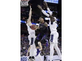 Washington's David Crisp, center, drives to the basket between Utah State's Quinn Taylor, left, and Neemias Queta in the first half during a first round men's college basketball game in the NCAA Tournament in Columbus, Ohio, Friday, March 22, 2019.